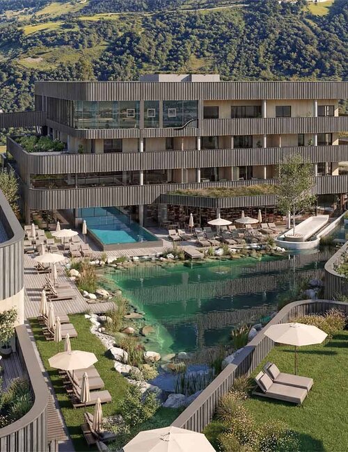 Mehrstöckiges modernes Hotelgebäude mit Holzfassade vor bewaldeten Berg und einem natürlichen Schwimmteich mit Liegestühlen und Sonnenschirmen auf einer Wiese