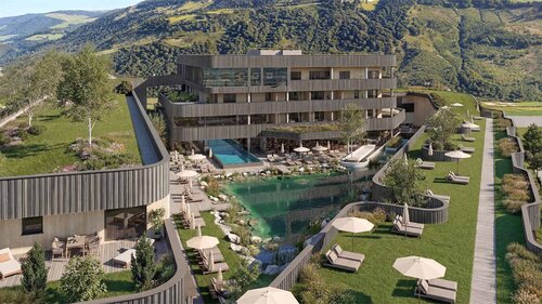 Mehrstöckiges modernes Hotelgebäude mit Holzfassade vor bewaldeten Berg und einem natürlichen Schwimmteich mit Liegestühlen und Sonnenschirmen auf einer Wiese