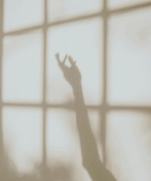 TheGreen-Fuellbilder-26 Schatten einer ausgestreckten Hand vor einem Fenster mit quadratischen Scheiben