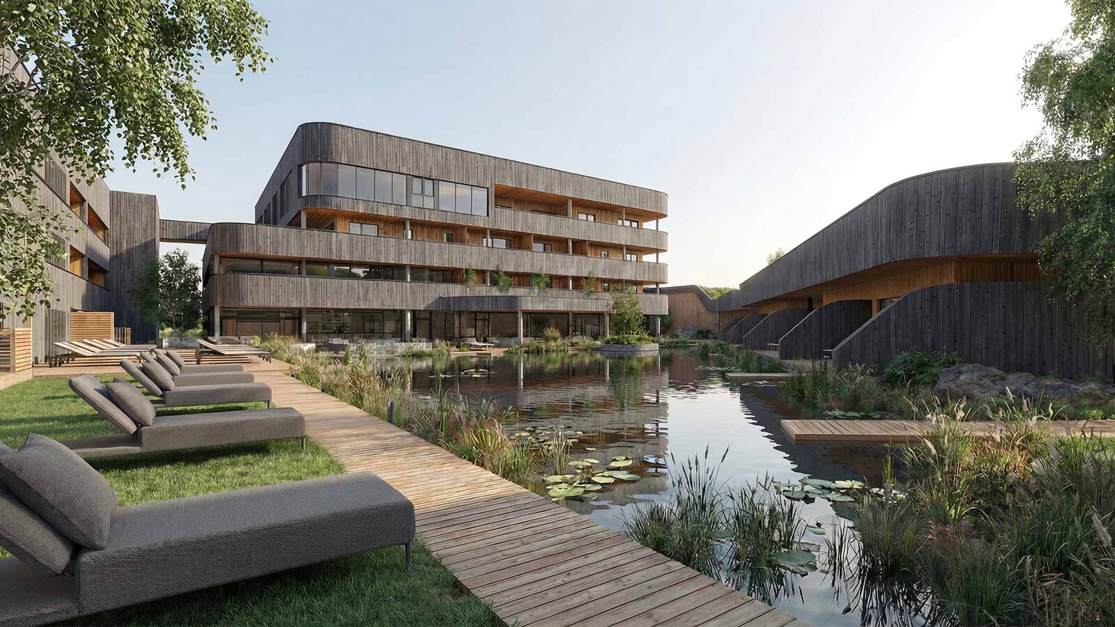 Moderner Gebäudekomplex mit Holzfassaden neben einem Teich mit Seerosen und einem Holzsteg mit Liegen