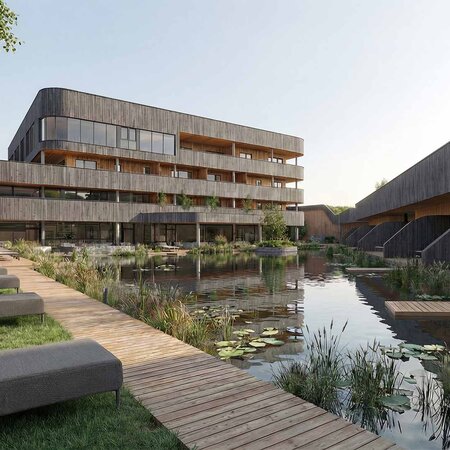 Moderner Gebäudekomplex mit Holzfassaden neben einem Teich mit Seerosen und einem Holzsteg mit Liegen