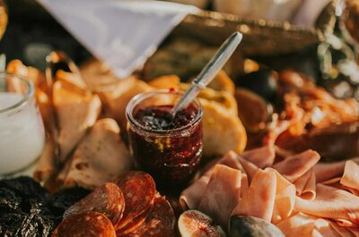 Brett mit verschiedenen Wurst- und Käsesorten, Feigen und einem Glas mit Marmelade und Löffel