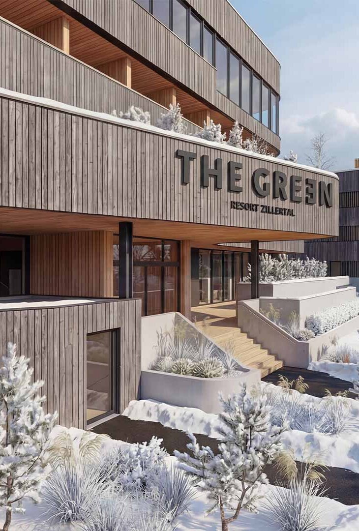 Holzfassade eines modernen Gebäudes mit dem Schriftzug 'THE GREEN' und schneebedeckten Bäumen und Wegen im Vordergrund