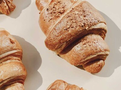 Mehrere Croissants mit knuspriger Kruste auf hellem Untergrund